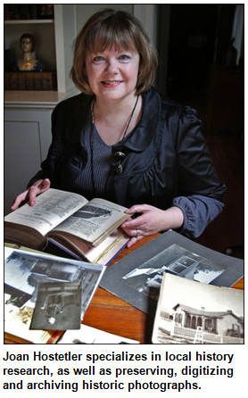 Joan Hostetler of Heritage Photo & Research Services at table with artifacts.