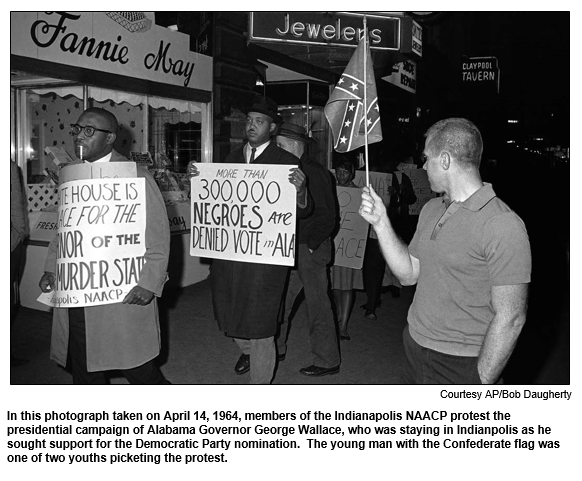 In this photograph taken on April 14, 1964, members of the Indianapolis NAACP protest the presidential campaign of Alabama Governor George Wallace, who was staying in Indianpolis as he sought support for the Democratic Party nomination.  The young man with the Confederate flag was one of two youths picketing the protest.
