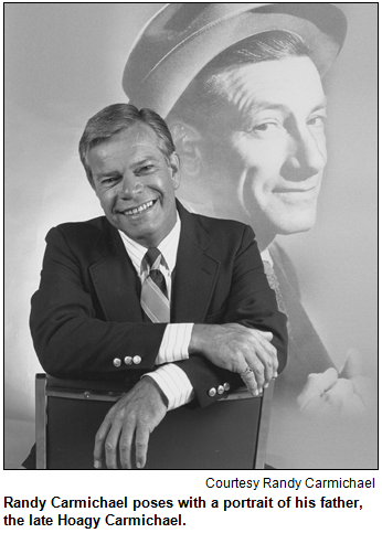 Randy Carmichael poses with a portrait of his father, the late Hoagy Carmichael. Image courtesy Randy Carmichael.